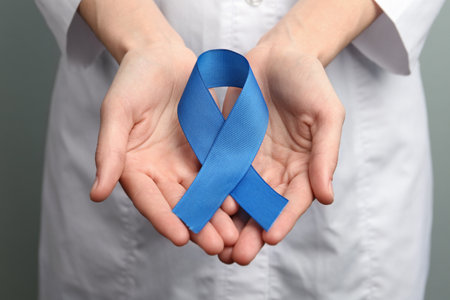 Doctor holding blue awareness ribbon, closeup view. Symbol of medical issuesの写真素材