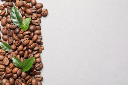 Fresh green coffee leaves and beans on light background, flat lay. Space for textの写真素材