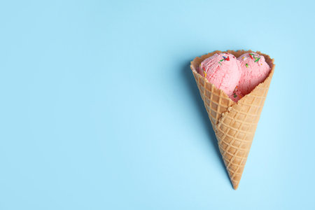Delicious ice cream in wafer cone on blue background, top view. Space for textの写真素材