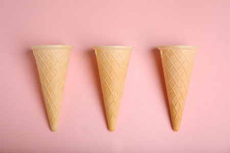 Empty wafer ice cream cones on pink background, flat layの写真素材