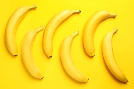 Ripe tasty bananas on yellow background, flat layの写真素材