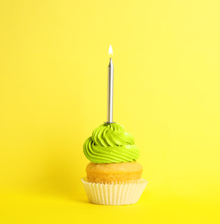 Birthday cupcake with candle on yellow backgroundの写真素材