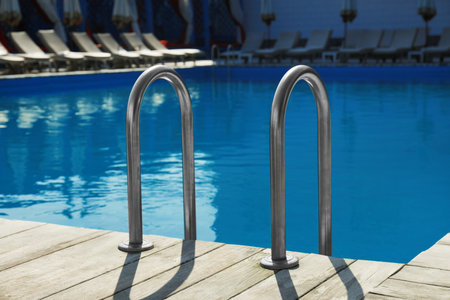 Modern swimming pool with ladder at resort