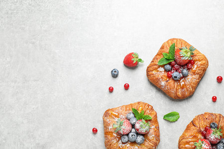 Fresh delicious puff pastry with sweet berries on light background, flat lay. Space for text