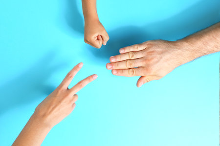 Family playing rock, paper and scissors on blue background, closeupの写真素材