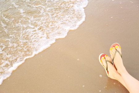 Closeup of woman with stylish flip flops on sand near sea, space for text. Beach accessoriesの写真素材