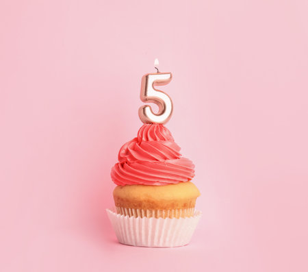 Birthday cupcake with number five candle on pink backgroundの写真素材