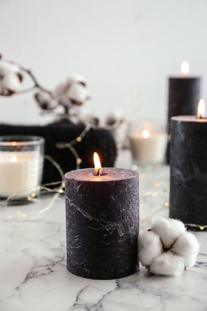 Burning candles and cotton flower with fairy lights on marble table, space for textの写真素材