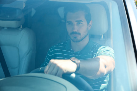 Attractive young man driving modern luxury carの写真素材