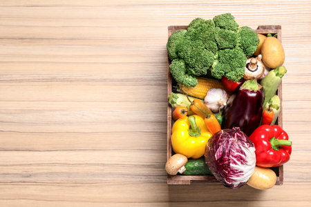 Crate with different fresh vegetables on wooden background, top view. Space for textの写真素材