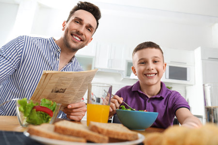 Dad and son having breakfast together in kitchenの写真素材