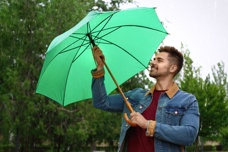 Man with umbrella outdoors on rainy dayの写真素材