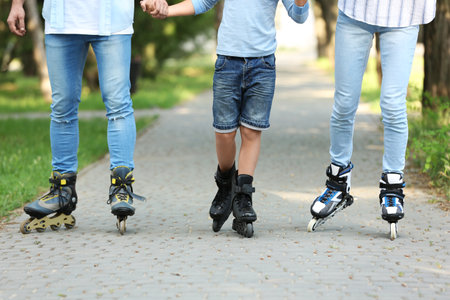 Young family roller skating in park, closeup of legsの写真素材