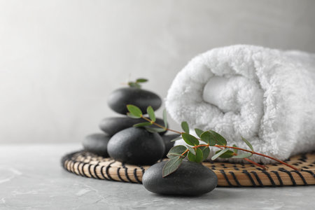 Composition with spa stones, towel and green leaves on gray table, space for textの写真素材