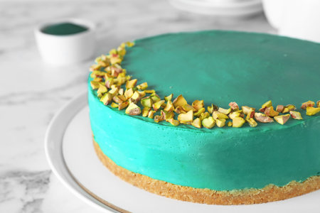 Delicious homemade spirulina cheesecake decorated with pistachios on marble tableの写真素材