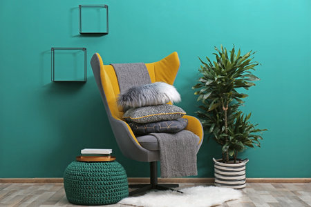 Armchair with plaid and pillows in cozy room interiorの写真素材