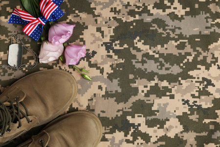 Flat lay composition with military boots and flowers on camouflage background, space for text. Armed Forces Dayの写真素材