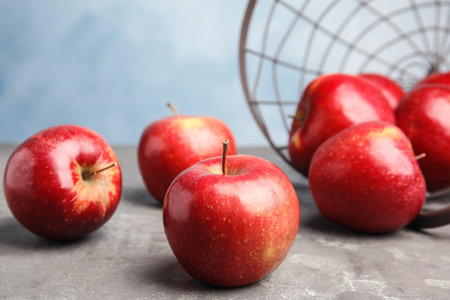 Ripe juicy red apples on gray table against blue background. Space for textの写真素材