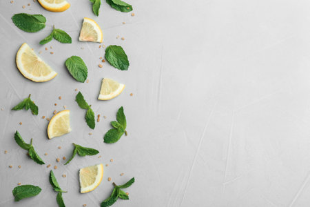 Fresh mint with sliced lemon and sugar on grey background, flat lay. Space for textの写真素材