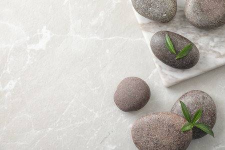 Flat lay composition with spa stones and green leaves on grey table, space for textの写真素材