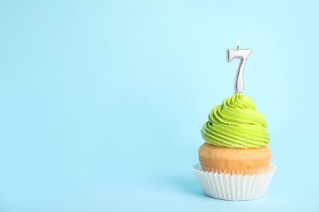 Birthday cupcake with number seven candle on blue background, space for textの写真素材