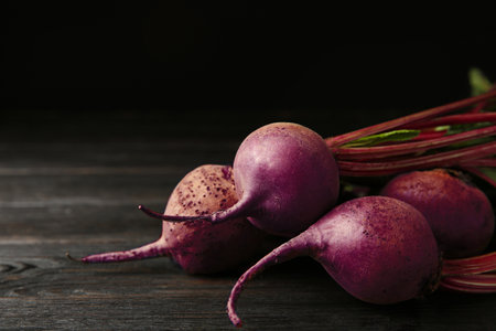 Fresh beets on dark wooden table against black background. Space for textの写真素材