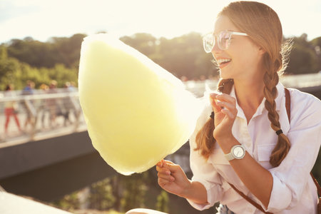 Young woman with cotton candy outdoors on sunny dayの写真素材