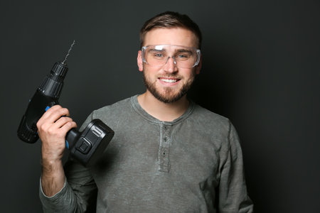 Young working man with power drill on dark backgroundの写真素材
