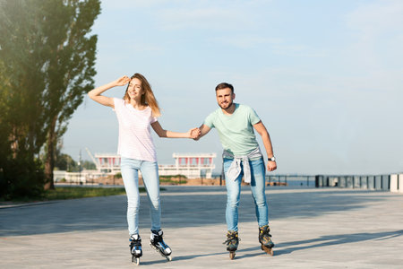 Young happy couple roller skating on city streetの写真素材