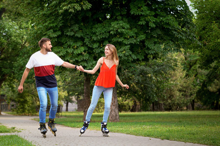 Young happy couple roller skating in summer park