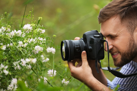Male photographer taking picture of beautiful plants with professional camera outdoorsの写真素材
