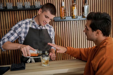 Bartender pouring whiskey for client at counter in pubの写真素材