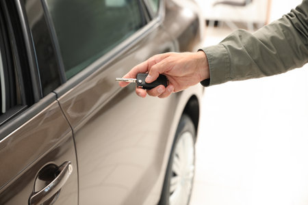 Young man checking alarm system with car key indoors, closeupの写真素材