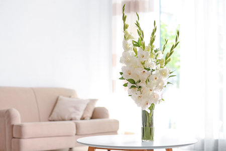 Vase with beautiful white gladiolus flowers on wooden table in living room. Space for textの写真素材