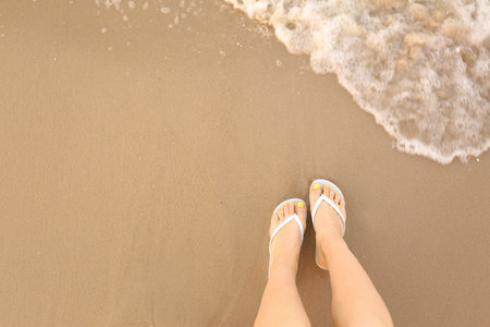 Top view of woman with white flip flops on sand near sea, space for text. beach accessoriesの写真素材