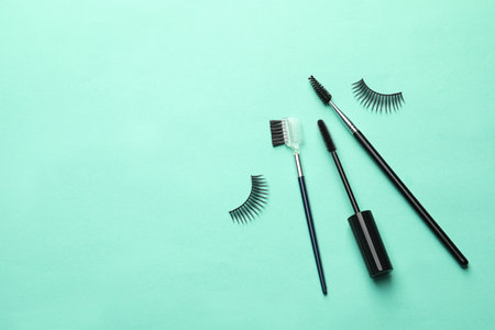 False eyelashes and brushes on turquoise background, flat lay. Space for textの写真素材