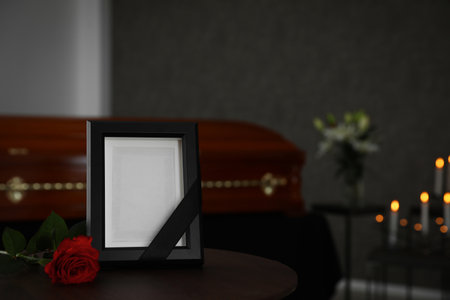 Black photo frame and red rose on table in funeral homeの写真素材