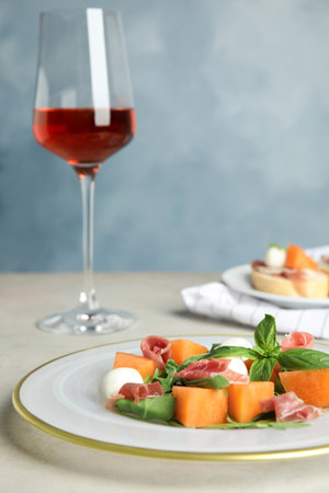 Fresh melon with prosciutto, mozzarella and basil on tableの写真素材