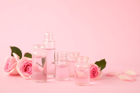 Bottles of essential oil and roses on pink background. Space for textの写真素材
