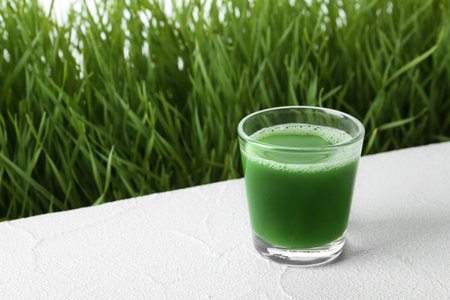 Glass of juice and fresh wheat grass on background. Space for textの写真素材