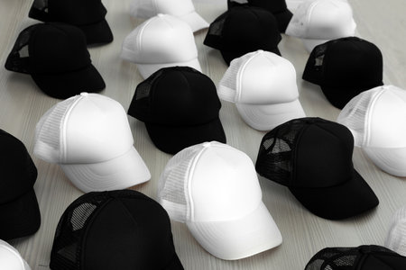 Many blank black and white caps on wooden table. Mock up designの写真素材