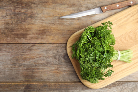 Cutting board with fresh green parsley and knife on wooden table, flat lay. Space for textの写真素材