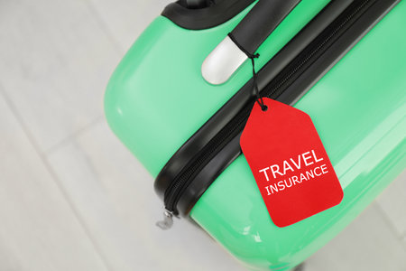 Suitcase with TRAVEL INSURANCE label on floor, top viewの写真素材