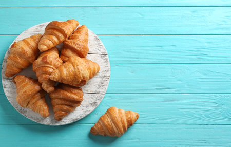 Board with tasty croissants and space for text on light blue background, flat lay. french pastryの写真素材