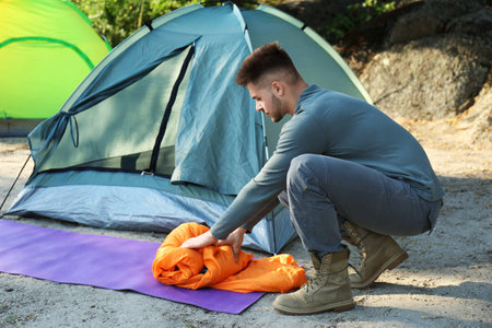 Young man sleeping bag near tent outdoorsの写真素材