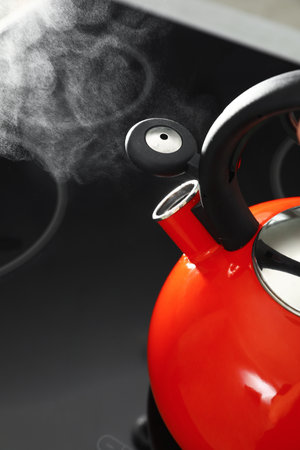 Modern kettle with whistle on stove, closeup. Space for text