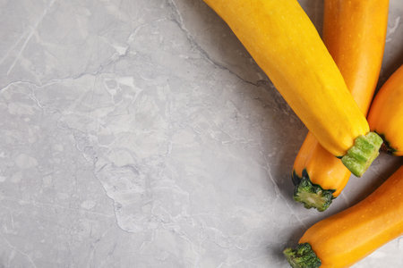 Fresh ripe yellow zucchini on gray marble background, flat lay. Space for textの写真素材