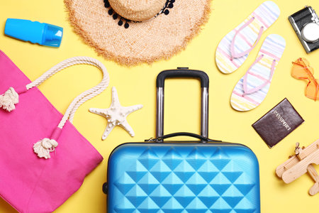 Flat lay composition with suitcase and beach objects on yellow backgroundの写真素材