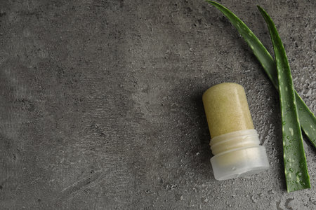 Natural crystal alum deodorant and aloe on gray table, flat lay. Space for text