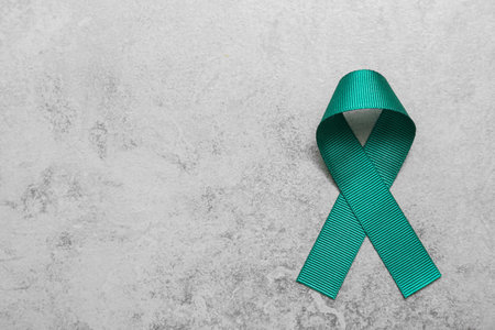 Teal awareness ribbon on gray background, top view with space for text. Symbol of social and medical issuesの写真素材